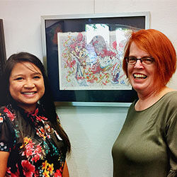 Journey of Hope Art Show 2019 writer Valerie Dacpano and artist Melani Grube in front of Melani's piece, "Flowing Over", inspired by Valerie's story of her mental health journey. Cropped for thumbnail image.